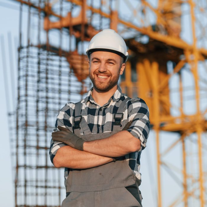 Happy worker is standing on the construction site at daytime.